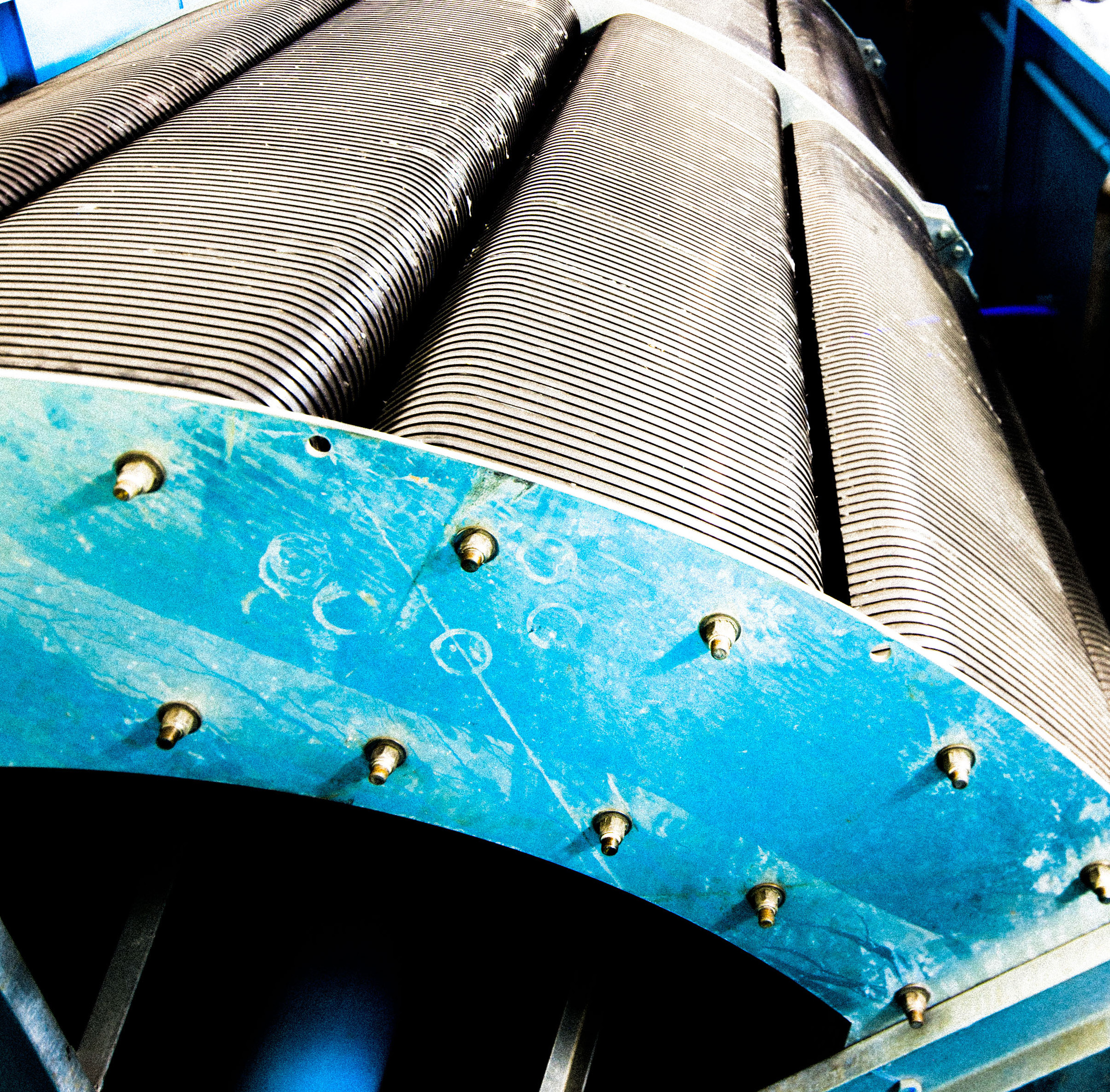 Close-up of a corrugated rotating aeration drum on a blue steel hub at a wastewater treatment plant