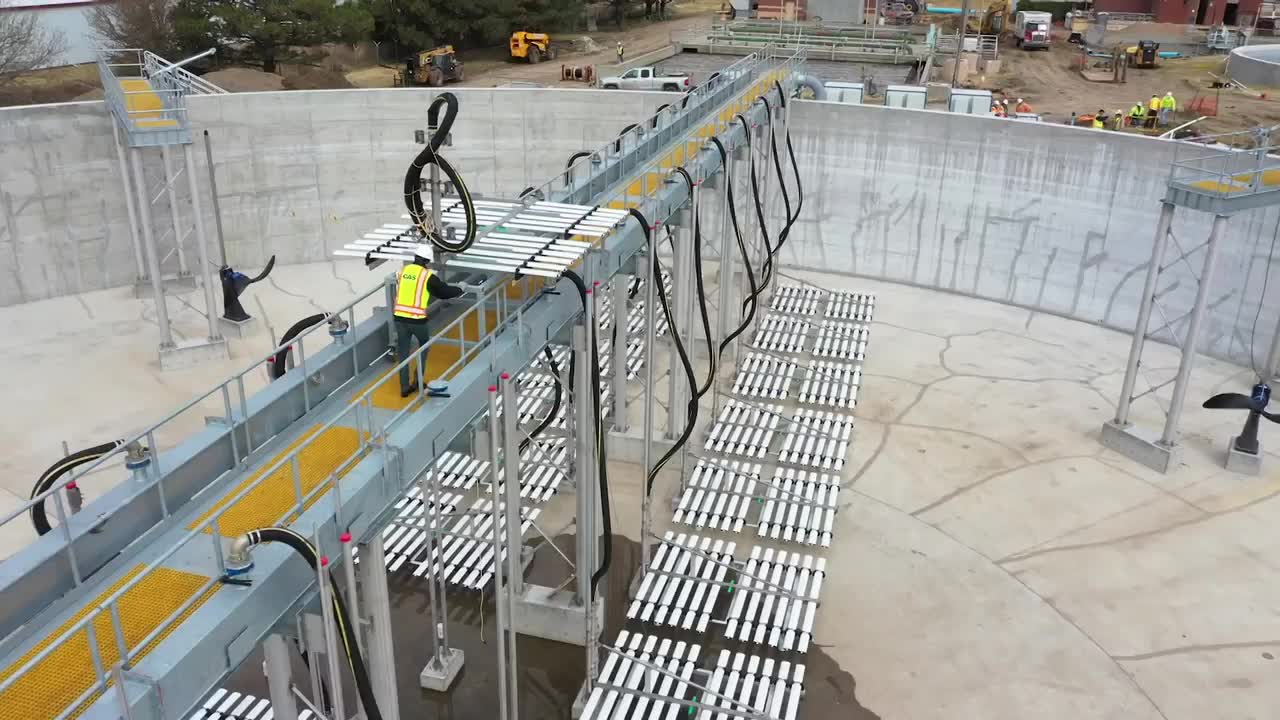 Jaeger Aeration OxyLift retrievable fine-bubble diffuser racks along a walkway in an empty concrete aeration basin during installation
