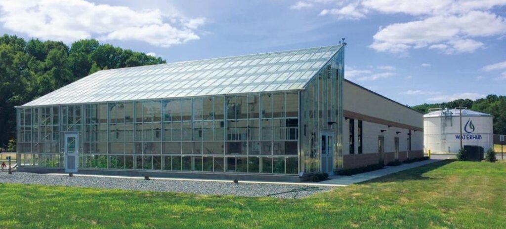 The WaterHub Approach to Sustainable Water Management in Texas Greenhouse-enclosed WaterHub water reuse facility with branded storage tank