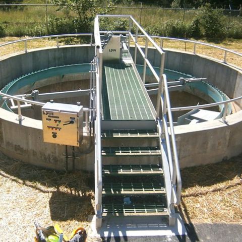Envirodyne bridge supported clarifier with access bridge, stairs, handrail and control panel on a small circular concrete tank